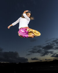 Junge Frau springt vor dem Abendhimmel in die Luft - STSF000941