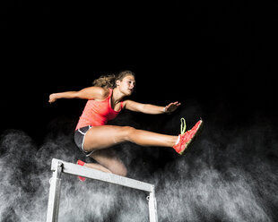 Young woman jumping over hurdle - STSF000945