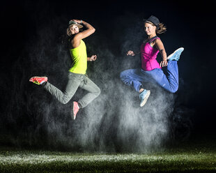 Zwei junge Frauen springen zwischen Mehlwolken in den Nachthimmel - STSF000947