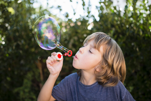 Blond little boy blowing soap bubbles - RAEF000510