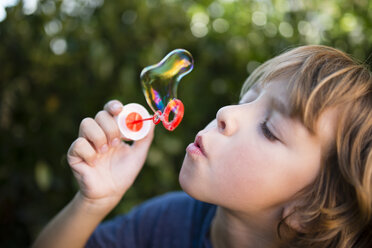 Blond little boy blowing soap bubble - RAEF000511