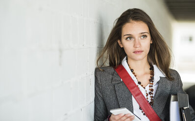 Young woman holding folder and cell phone - UUF005750