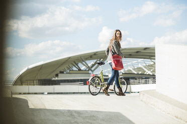 Junge Frau schiebt Fahrrad - UUF005764