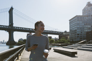 USA, New York City, portrait of young woman with smartphone and coffee to go - GIOF000140