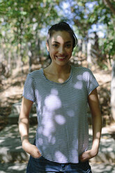 Portrait of smiling young woman with hands in pockets - GIOF000145