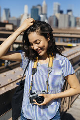 USA, New York City, Porträt einer lächelnden jungen Frau mit Kamera - GIOF000151