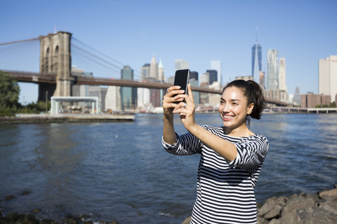 USA, New York City, junge Frau macht ein Selfie mit Smartphone, lizenzfreies Stockfoto