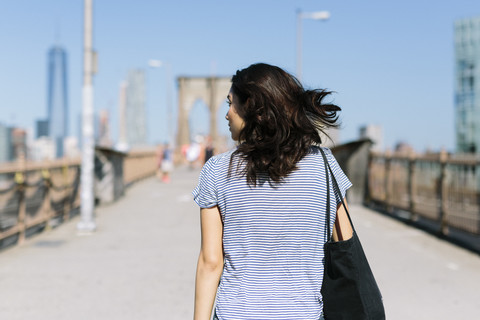 USA, New York City, Rückenansicht einer jungen Frau auf der Brooklyn Bridge, lizenzfreies Stockfoto