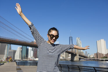 USA, New York City, portrait of happy young woman balancing with outstretched arms - GIOF000165