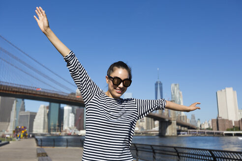 USA, New York City, Porträt einer glücklichen jungen Frau, die mit ausgestreckten Armen balanciert - GIOF000165