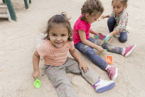 Drei kleine Mädchen spielen im Sandkasten auf einem Spielplatz, lizenzfreies Stockfoto