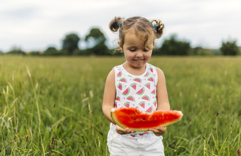 Kleines Mädchen mit Wassermelonenscheibe, lizenzfreies Stockfoto