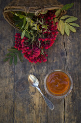 Wickerbasket, rowanberries and glass of rowanberry jam on dark wood - LVF003936