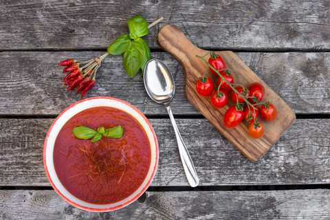 Schale mit hausgemachter Tomatensuppe mit Chilifäden auf Holz, lizenzfreies Stockfoto