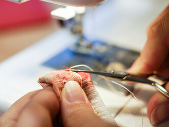 Close-up of woman cutting thread at sewing machine - HOHF001352