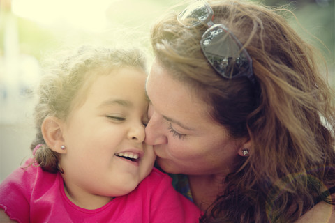 Woman cuddling with her little daughter stock photo