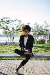 USA, New York City, portrait of smiling businesswoman sitting on a bench with digital tablet - GIOF000179