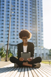 USA, New York City, smiling businesswoman sitting on a bench using digital tablet - GIOF000185