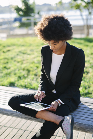 USA, New York City, Geschäftsfrau, die auf einer Bank sitzt und ein digitales Tablet benutzt, lizenzfreies Stockfoto