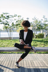 USA, New York City, businesswoman sitting on a bench using digital tablet - GIOF000206