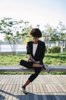 USA, New York City, businesswoman sitting on a bench using digital tablet - GIOF000206