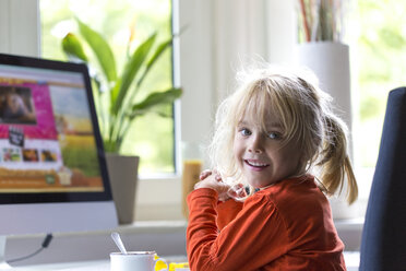 Porträt eines blonden kleinen Mädchens, das vor einem Computer sitzt - JFEF000702