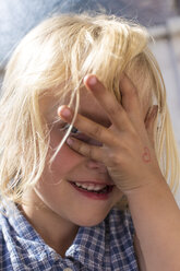 Blond little girl peeking through her fingers - JFEF000704