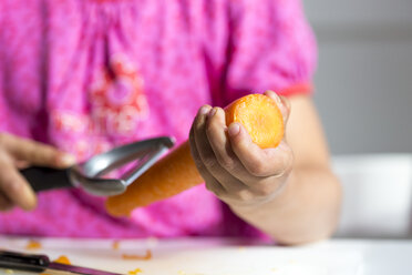 Little girl peeling a carrot, close-up - JFEF000706