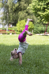 Little girl turning wheels on a meadow - JFEF000710