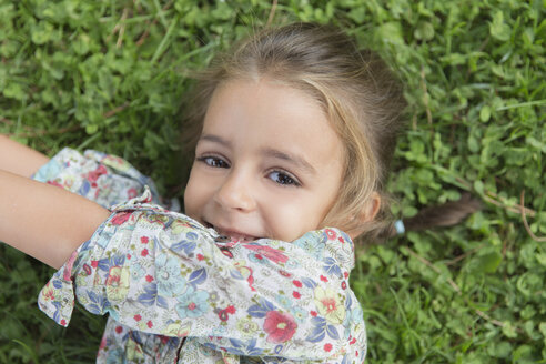 Porträt eines lächelnden kleinen Mädchens, das auf einer Wiese liegt - ERLF000055