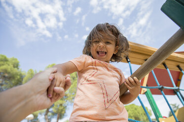 Porträt eines lächelnden kleinen Mädchens auf einem Spielplatz, das von der Hand seines Vaters gehalten wird - ERLF000058