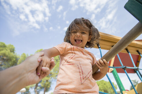 Portrait of smiling little girl on a playground being held by her father's hand - ERLF000058