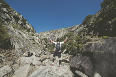 Spanien, Ultra-Trail-Läufer, der mit erhobenen Händen die Landschaft betrachtet und den Sieg feiert - RAEF000523