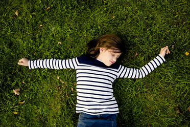 Girl wearing striped sweatshirt lying on a meadow with closed eyes - LVF003955