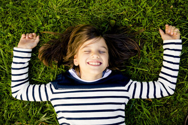 Portrait of girl wearing striped sweatshirt lying on a meadow with closed eyes - LVF003958