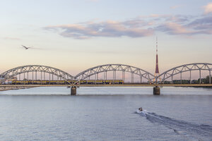 Lettland, Riga, Eisenbahnbrücke und Fernsehturm an der Daugava am Abend - MELF000083