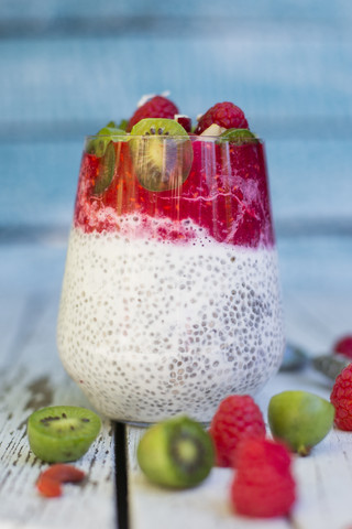 Glas Chia-Pudding mit Kokos, Himbeersauce und verschiedenen Früchten, lizenzfreies Stockfoto