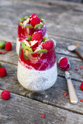 Two glasses of chia pudding with cocos, raspberry sauce and several fruits - SARF002169