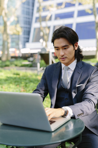 USA, New York City, Manhattan, Geschäftsmann arbeitet mit einem Laptop im Bryant Park, lizenzfreies Stockfoto