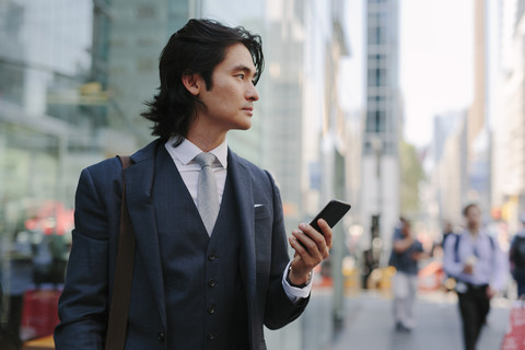 USA, New York City, Geschäftsmann mit Mobiltelefon in Manhattan, lizenzfreies Stockfoto