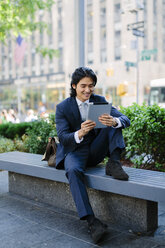 USA, New York City, Manhattan, lächelnder Geschäftsmann mit Blick auf eine digitale Tafel - GIOF000224