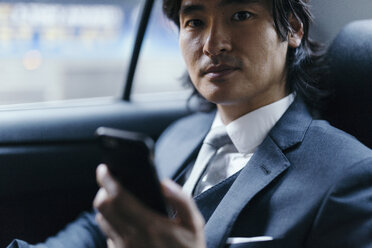 Porträt eines Geschäftsmannes auf dem Rücksitz eines Autos mit Mobiltelefon - GIOF000227