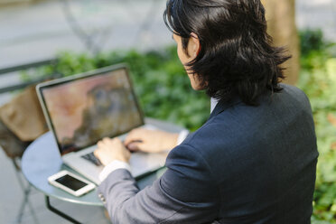 USA, New York City, Manhattan, Geschäftsmann arbeitet mit einem Laptop im Bryant Park - GIOF000236