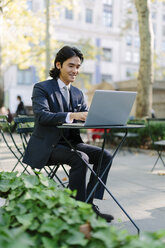 USA, New York City, Manhattan, smiling businessman working with a laptop in Bryant Park - GIOF000247