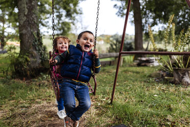 Zwei kleine Kinder spielen mit Schaukel in einem Garten - MGOF000809