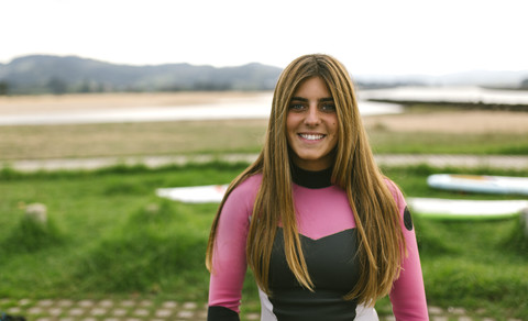 Spanien, Asturien, Villaviciosa, Porträt einer lächelnden jungen Frau an der Küste, lizenzfreies Stockfoto
