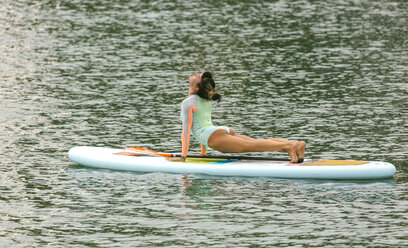 Woman practicing paddle board yoga - MGOF000820