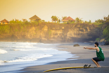 Indonesien, Bali, Surfer am Strand macht eine Kniebeuge - KNTF000105