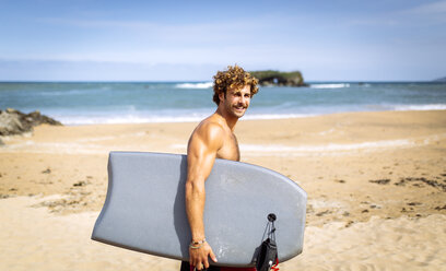 Spanien, Asturien, Colunga, lächelnder Surfer mit Bodyboard am Strand - MGOF000831