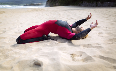 Spanien, Asturien, Colunga, Surfer, die sich am Strand strecken, lizenzfreies Stockfoto